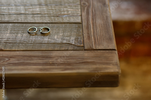 Wedding rings lie on the corner of wooden table