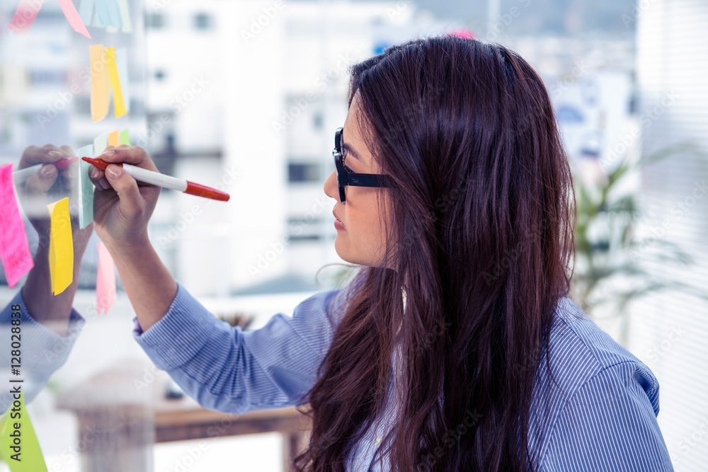 Asian businesswoman using sticky notes on wall Asian businesswoman using sticky notes on wall
