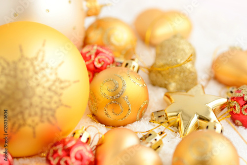 Christmas gold and red ornaments on the snow. Festive Christmas background