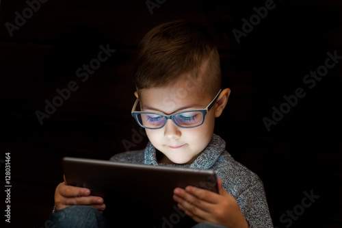 Child reads the e-book. Little boy looks at the screen of the ta photo