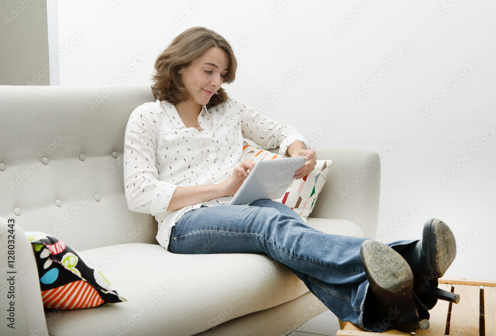 Beautiful young woman woman with a tablet in the sofa