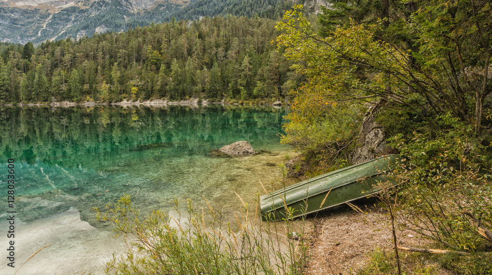 Obraz premium crystal clear mountain lake at sunset with light and sun filtering.Lake Tovel in Autumn. Italy