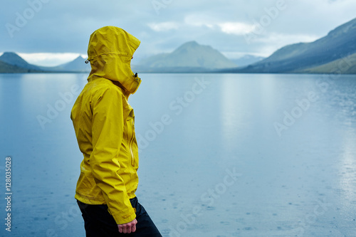 woman on the Lake coast with mountain reflection at the rainy day, Iceland