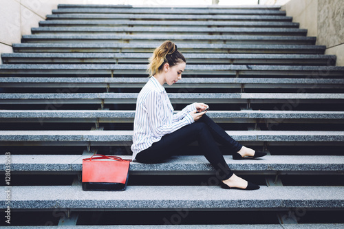 Young woman using smartphone while sitting on steps