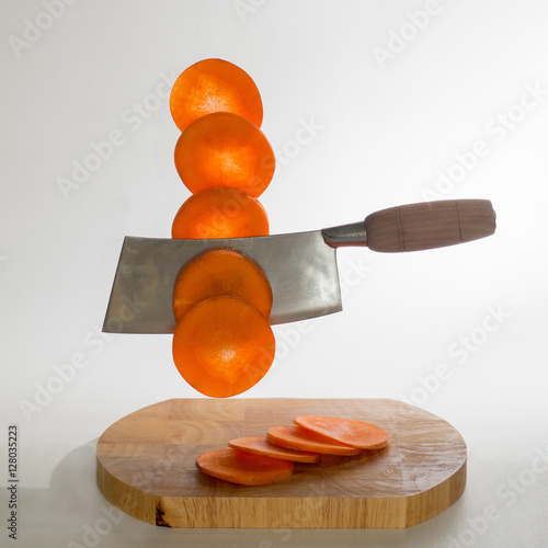 Chinese caidao cleaver knife cuts carrots on a white background photo