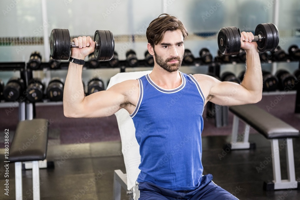 Muscular man lifting dumbbells on bench Muscular man lifting dumbbells on bench
