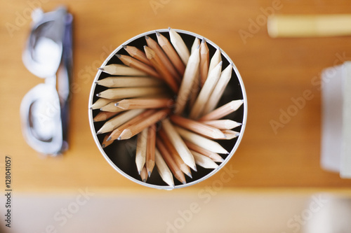 A can of lead pencils and sunglasses on a desk.