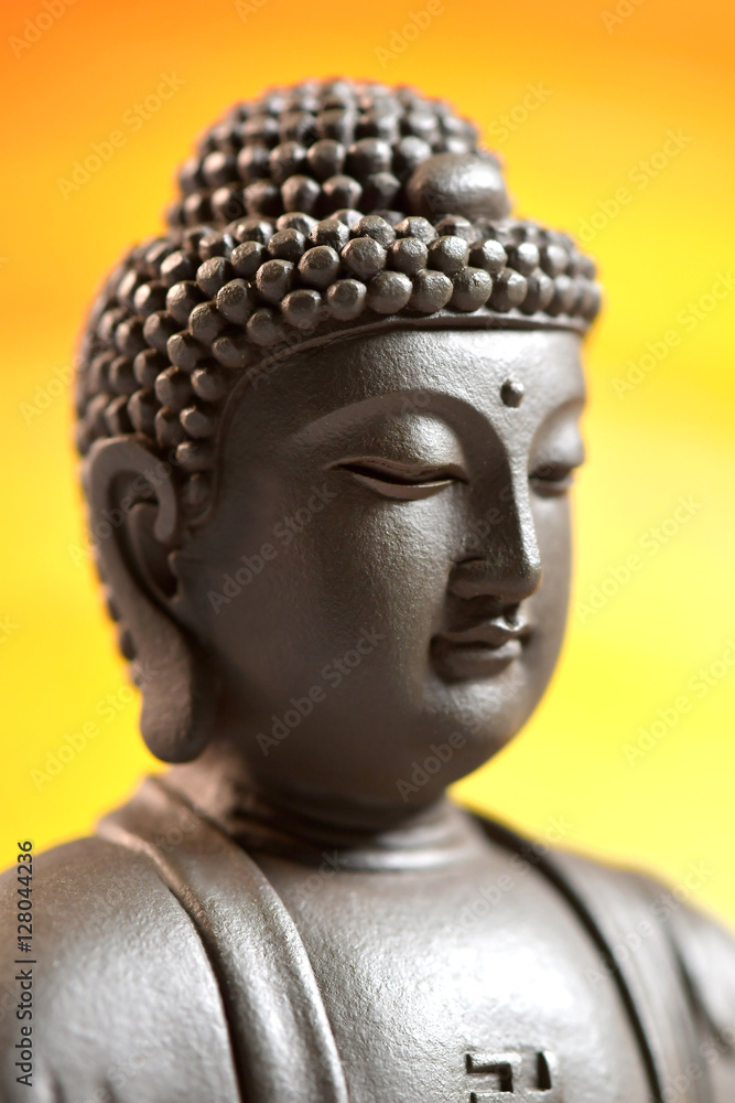 The face of Buddha Zen sculpture on a yellow background