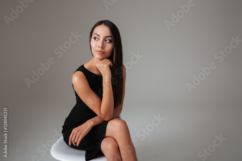Woman in black dress sitting on chair and looking away