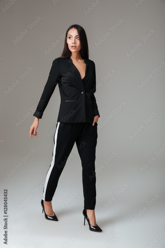 Smart attractive woman in black suit walking and looking away Smart attractive woman in black suit walking and looking away
