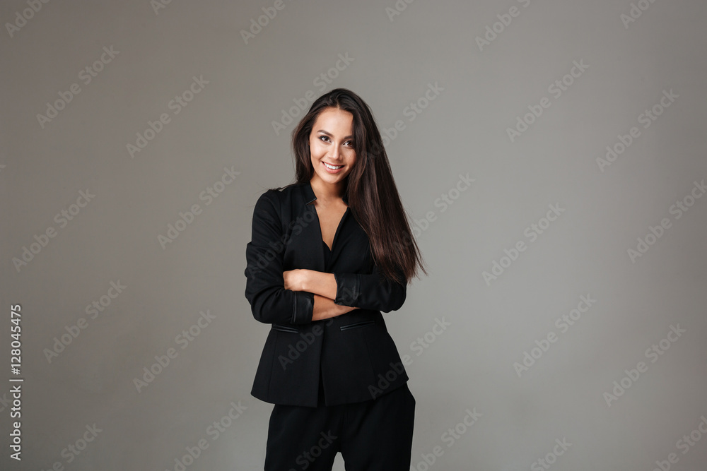 Smiling brunette woman in black suit standing with arms folded Smiling brunette woman in black suit standing with arms folded