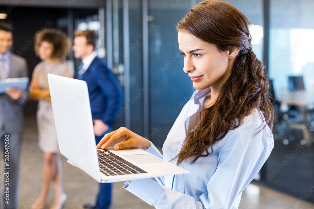 Confident businesswoman using laptop in office Confident businesswoman using laptop in office