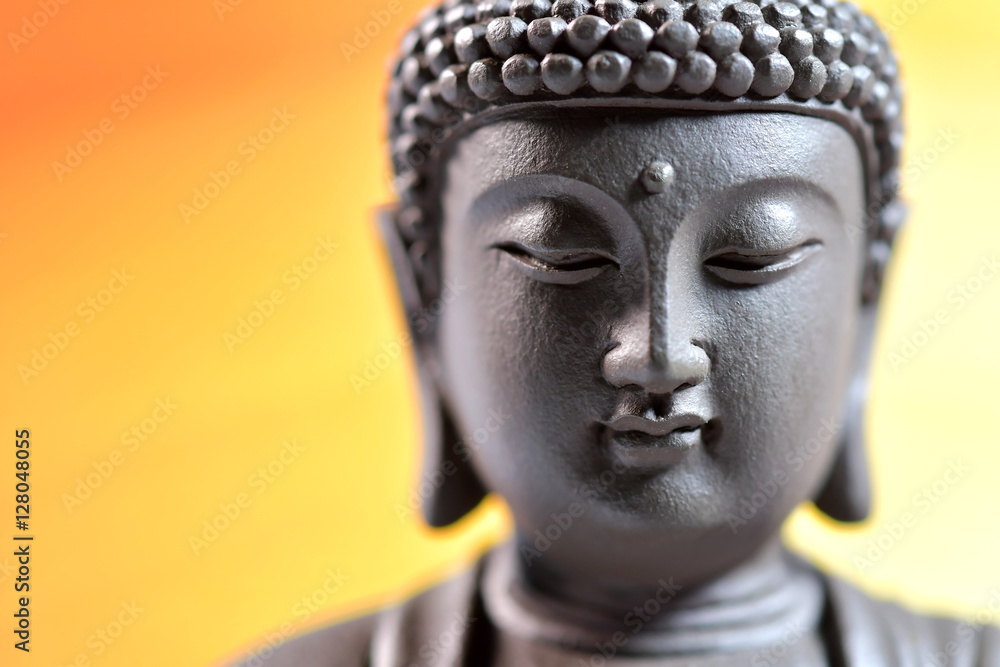 The face of Buddha Zen sculpture on a yellow background
