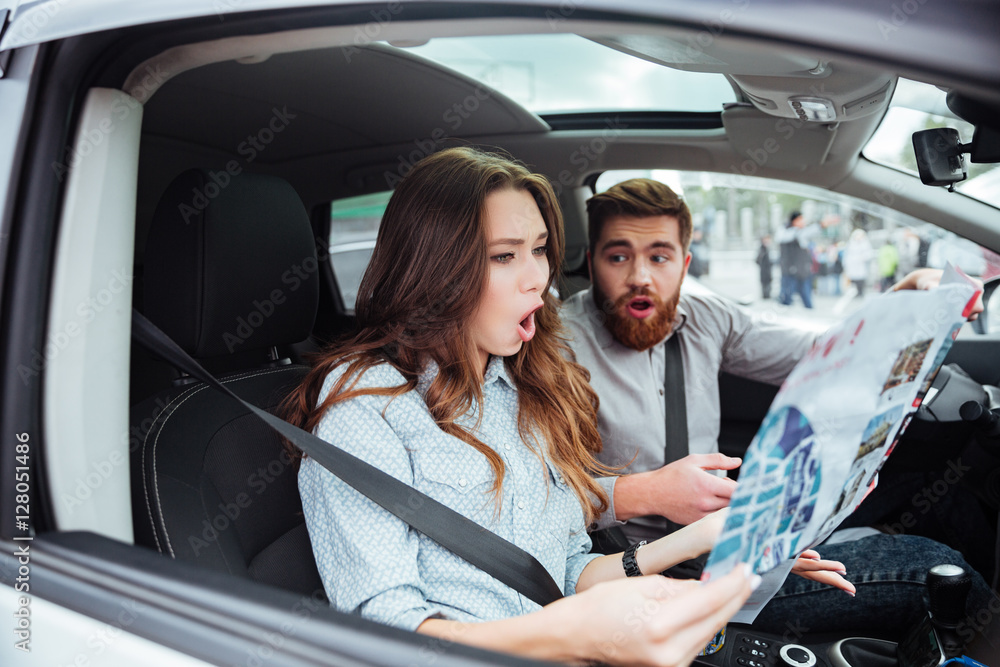 Surprised couple in car with map