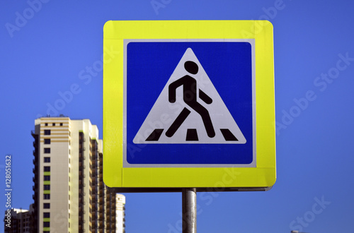 Road sign of the transition on the background of the city buildings and blue sky