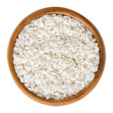Arborio rice in wooden bowl. Italian short-grain rice with rounded grains and higher starch content, used for risotto and pudding. Isolated macro food photo close up from above on white background.