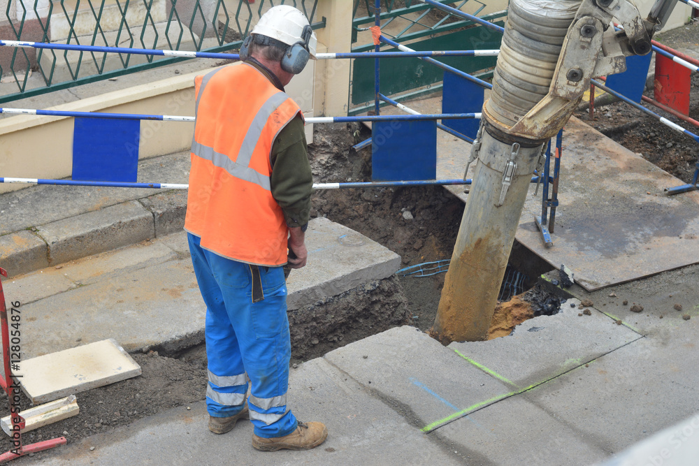 Asphalt worker controls the drilling process. Breaking concrete at road construction site Asphalt worker controls the drilling process. Breaking concrete at road construction site