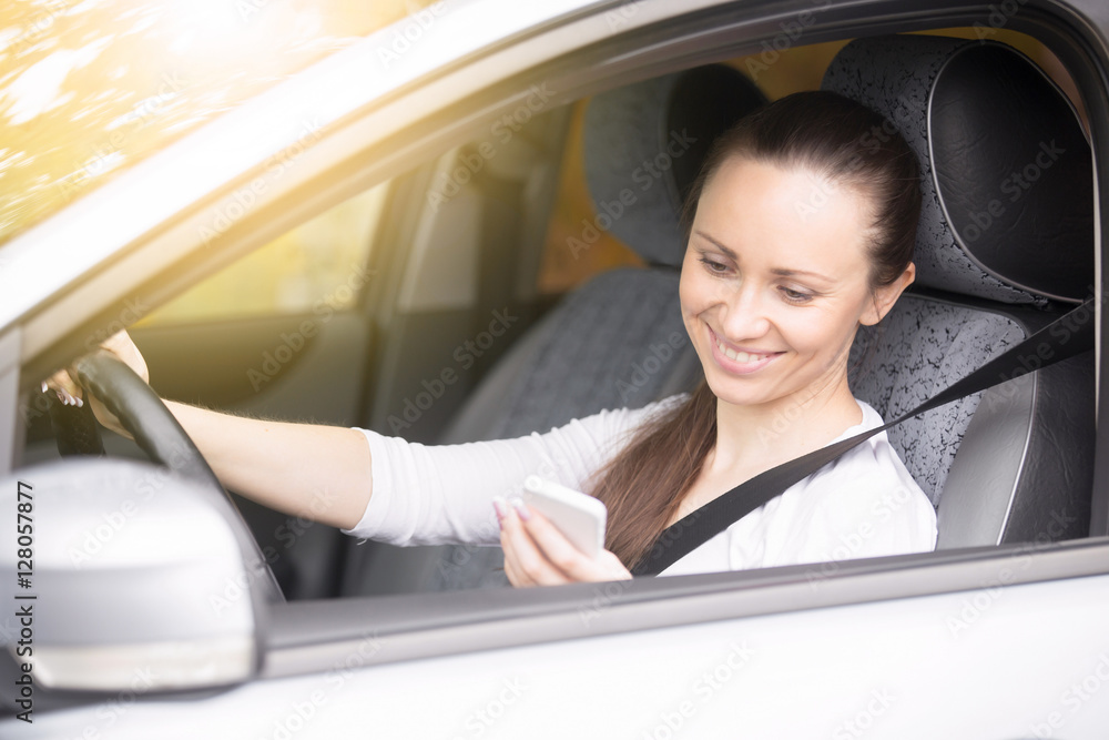 Young smiling woman looking at her phone screen traveling by car, using navigation app to find way