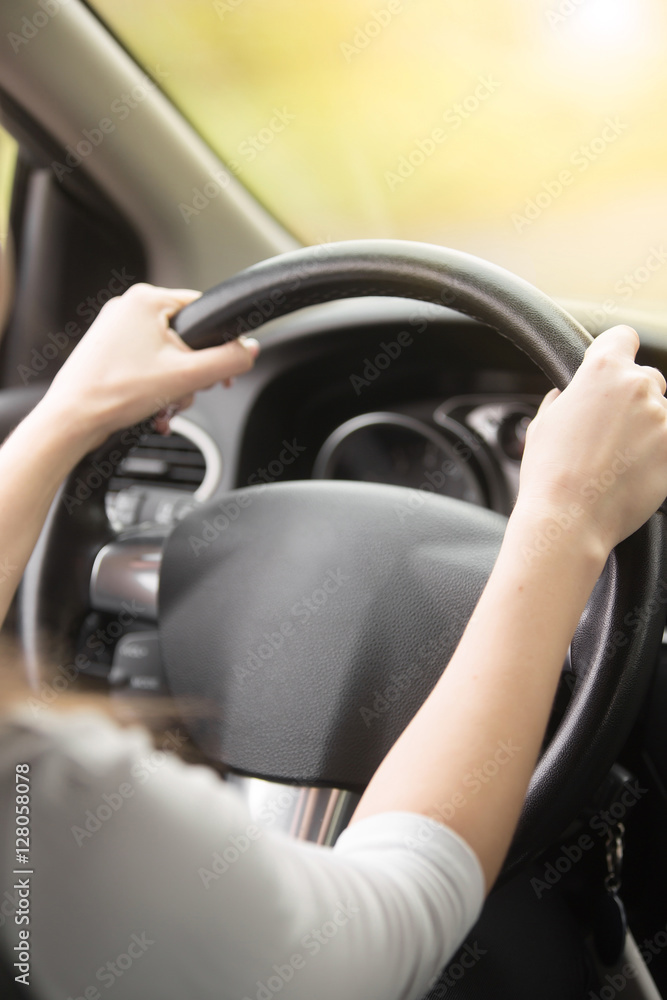 Close up of female hands on the steering. Traveler girl on car trip, looking at the road. View over shoulder. Vertical image