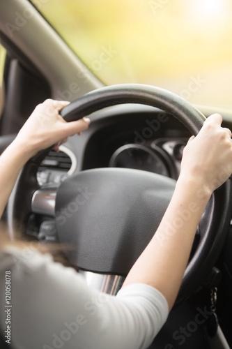 Close up of female hands on the steering. Traveler girl on car trip, looking at the road. View over shoulder. Vertical image