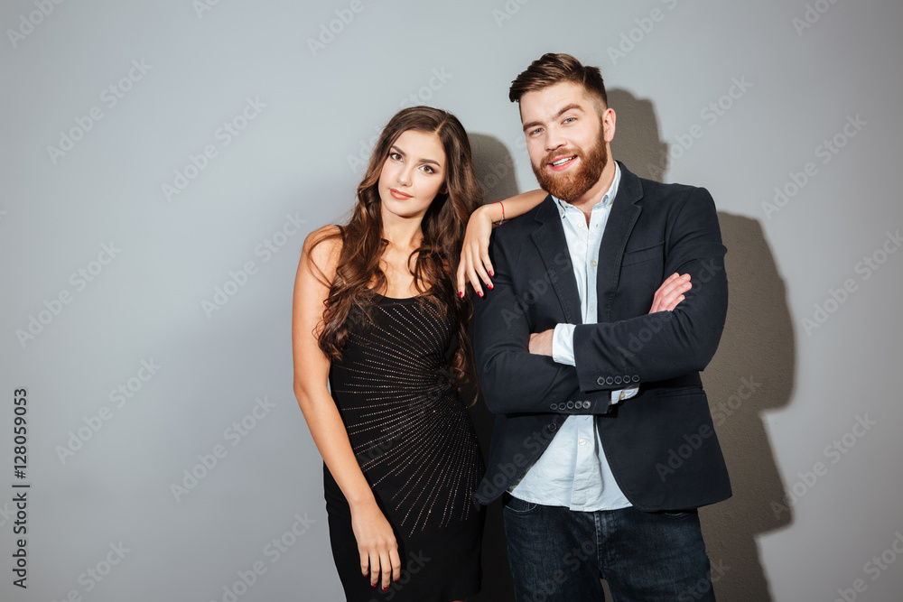 Couple in smart wear standing together and looking at camera Couple in smart wear standing together and looking at camera