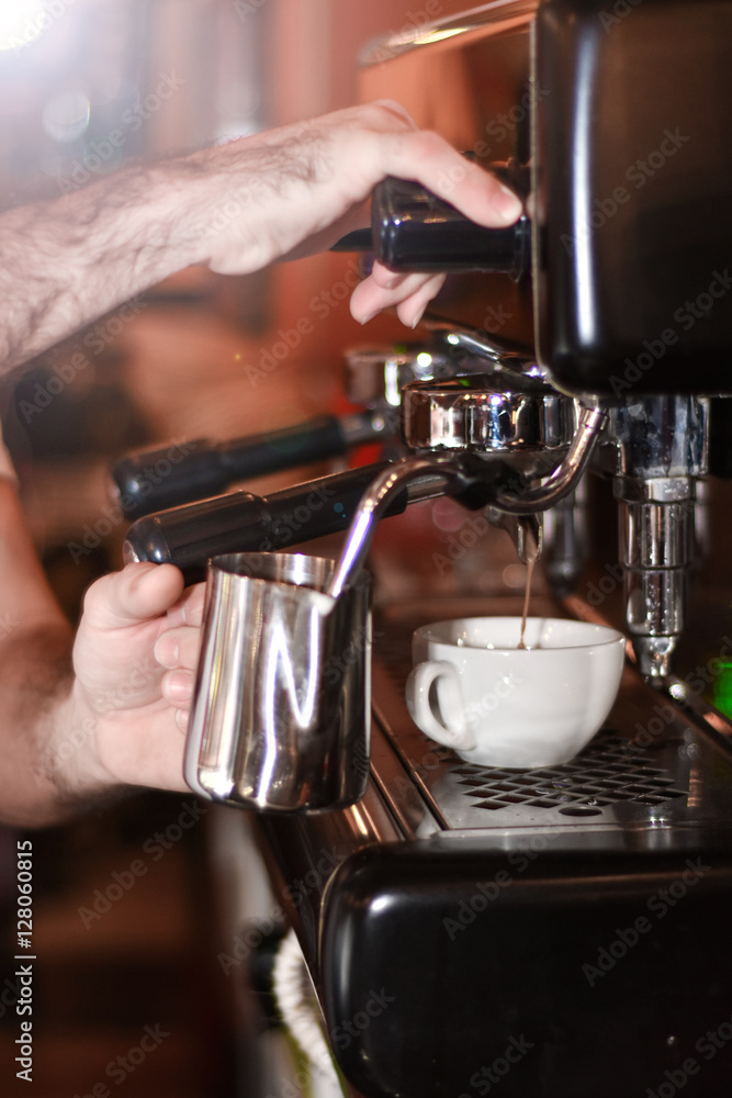 Barista prepares cappuccino in his coffeeshop; close-up