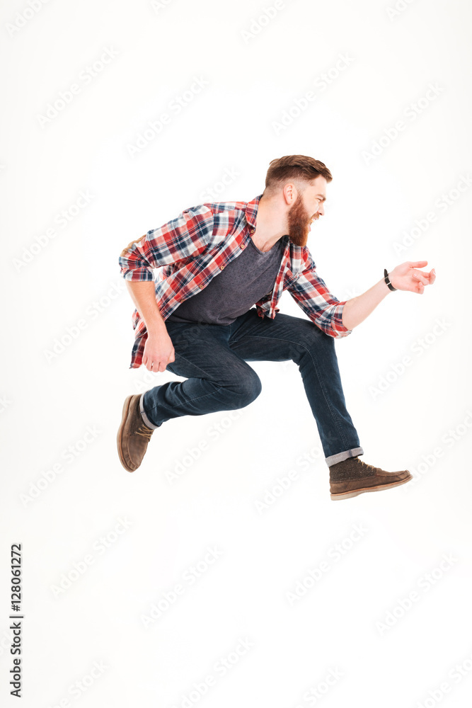 Young bearded man jumping and playing on invisible guitar
