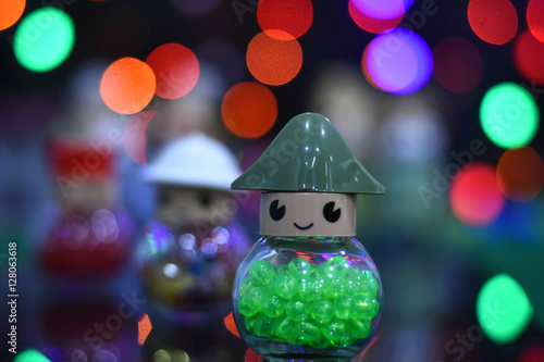 Glass beads in glass jar on colorful bokeh blurred background. Christmas and New Year's toys on on colorful background.