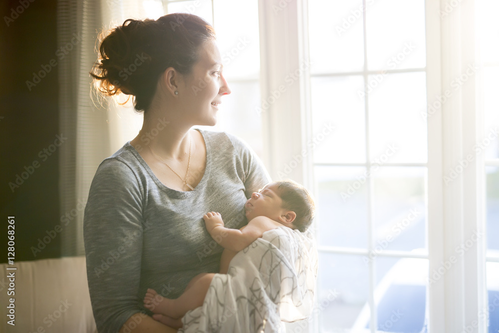 Happy mother holding adorable child baby on the living room