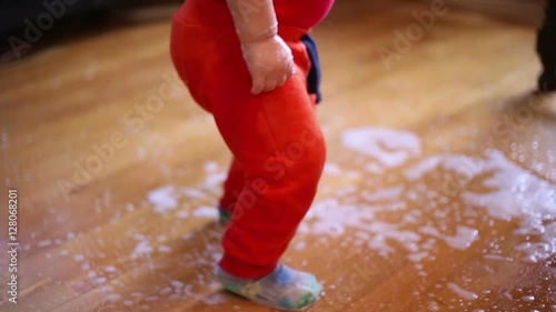 Cute baby boy  playing with spilled water on the floor at home, leg close
 