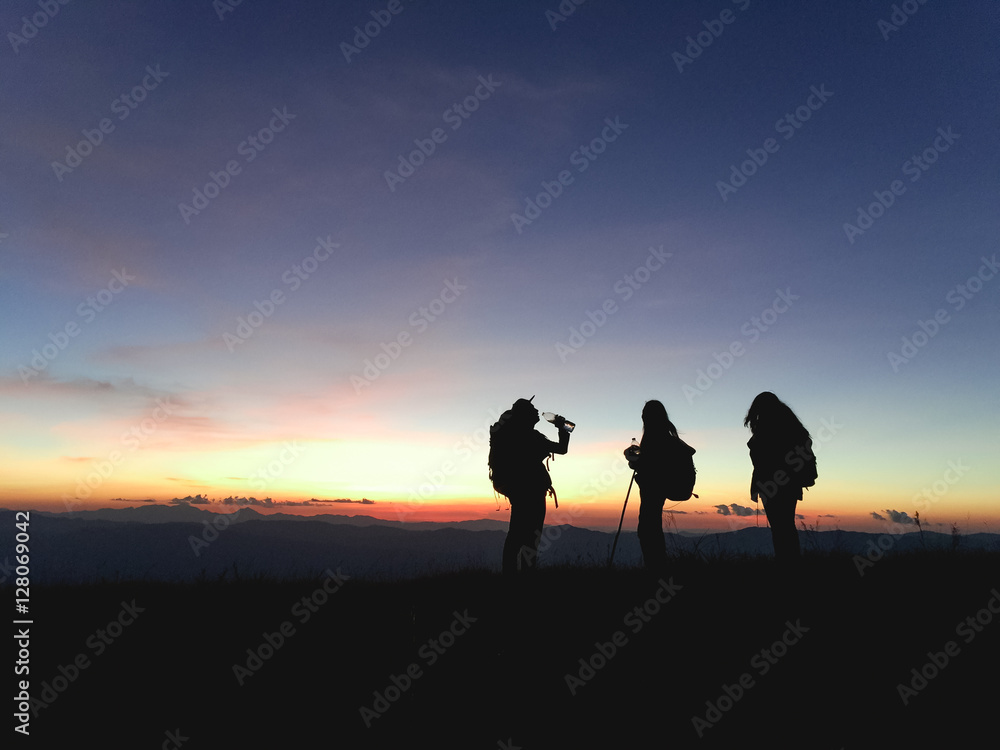 Silhouettes of group hikers people with backpacks enjoying sunset view from top of a mountain. Travel concept, Vintage filtered image.