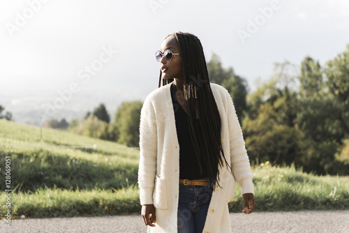 african woman in white sweater and sunglasses near meadow