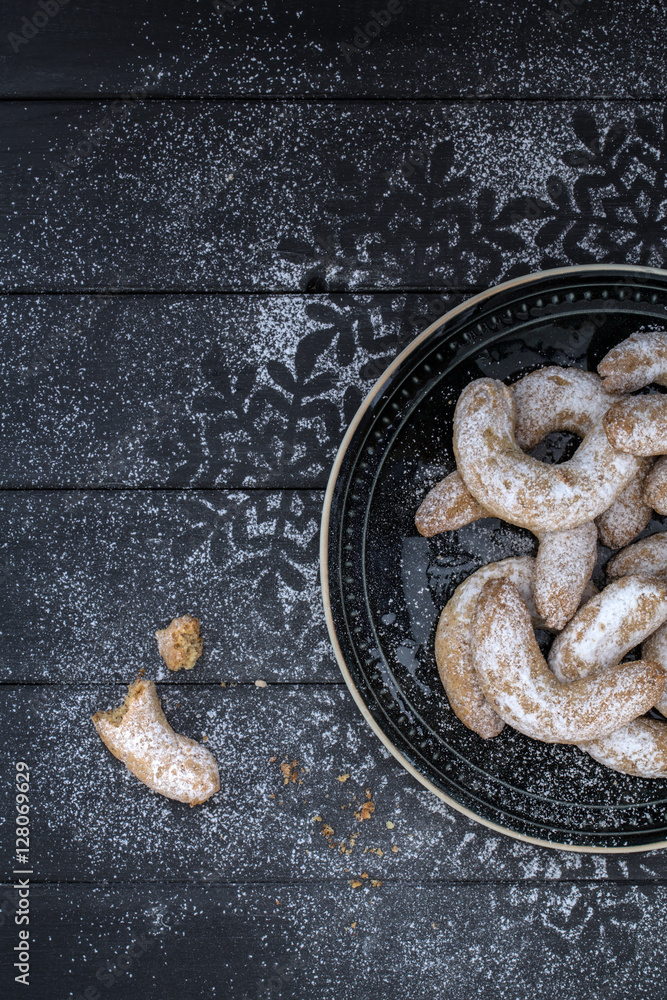 Vanillekipferl weihnachtlich geschmückt auf einem grauen Holzuntergrund