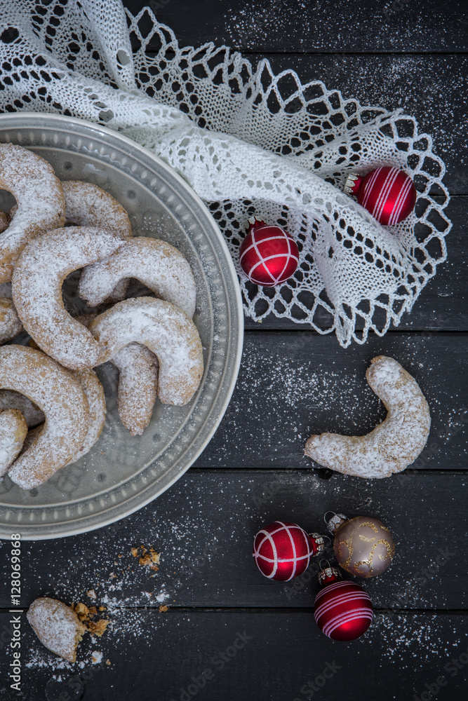 Vanillekipferl weihnachtlich geschmückt auf einem grauen Holzuntergrund