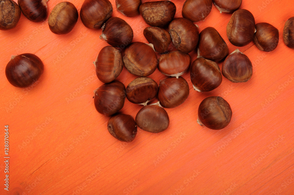 raw chestnuts on orange wooden background raw chestnuts on orange wooden background