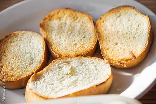 Pile of toasted bread slices on a single white plate.