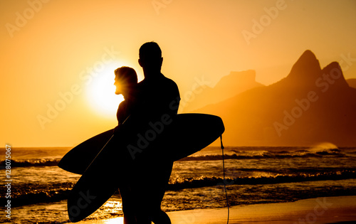 Golden sunset in Ipanema Beach with Two Brothers, Dois Irmaos, Mountain and two surfers silhouettes, Rio de Janeiro, Brazil