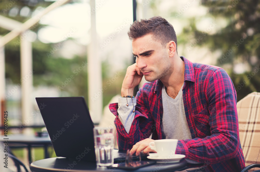 Young man sitting in a cafe on a coffee break. using phone Young man sitting in a cafe on a coffee break. using phone