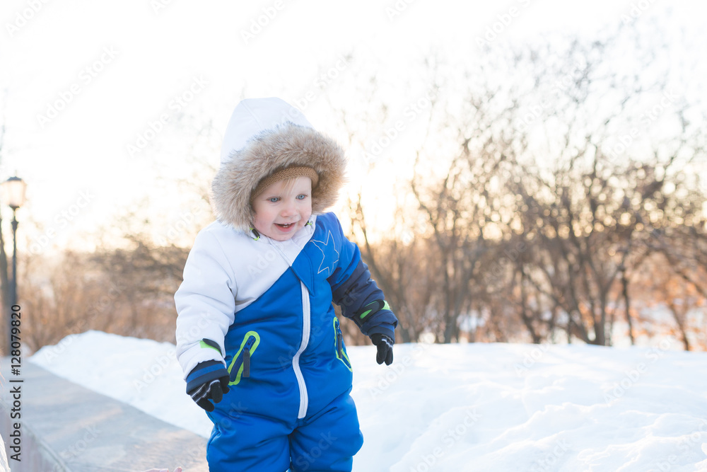 Little toddler boy playing with snow outdoors on beautiful winter day