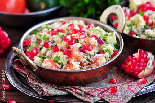 Healthy salad with couscous, tomato, avocado, red onion, pomegranate and olive oil. Eastern cuisine.