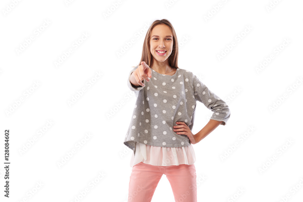 Cheerful young girl pointing at you standing in a confident pose Cheerful young girl pointing at you standing in a confident pose