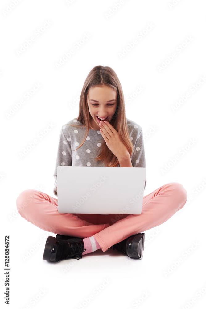 Surprised young girl holding hand near mouth using a laptop whil Surprised young girl holding hand near mouth using a laptop whil