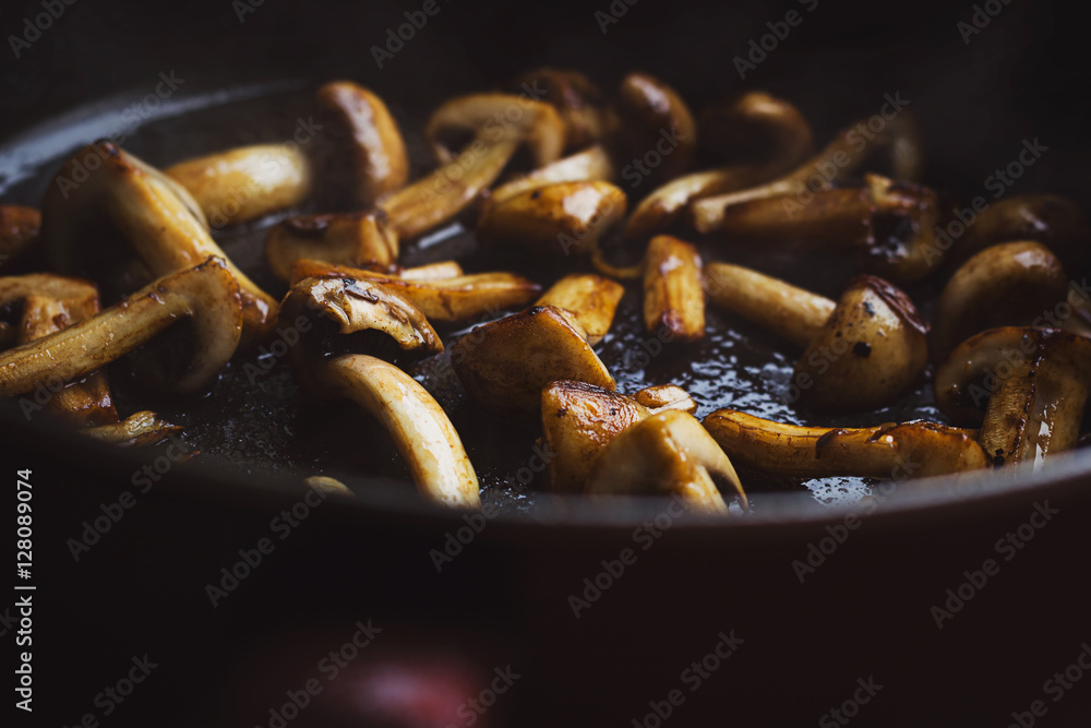 Fototapeta premium Roasted button mushrooms in a hot black frying pan