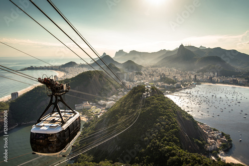 View of Rio de Janeiro city from the Sugarloaf Mountain by sunset with a cable car approaching