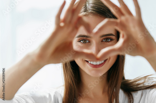 Fototapeta Naklejka Na Ścianę i Meble -  Beautiful Happy Woman Showing Love Sign Near Eyes.