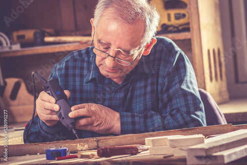 Senior carpenter carving wood with engraver tool. Restoring the old furniture.