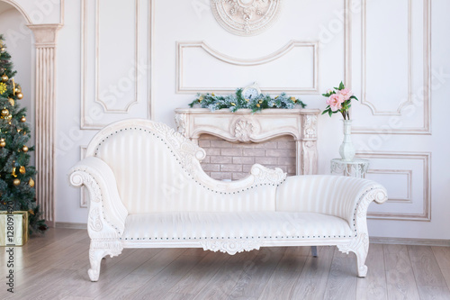 Christmas morning. classic apartments with a white fireplace, decorated tree, bright sofa, large windows