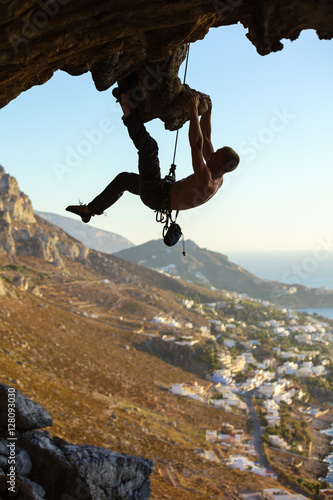 Young man climbing on roof of cave 