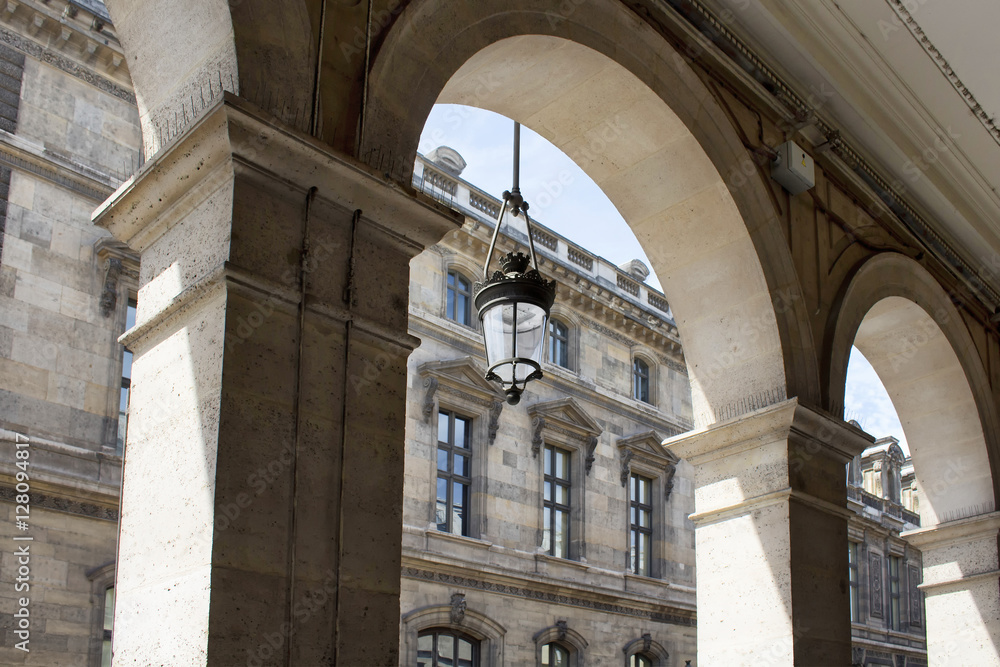 Old, traditional street lamp hung on a arch of a building in Paris. Shadows create dramatic feeling.