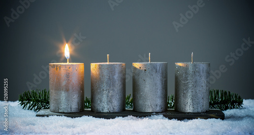Erste Advent - Vier silberne Adventskerzen mit einer Angezündete Kerze